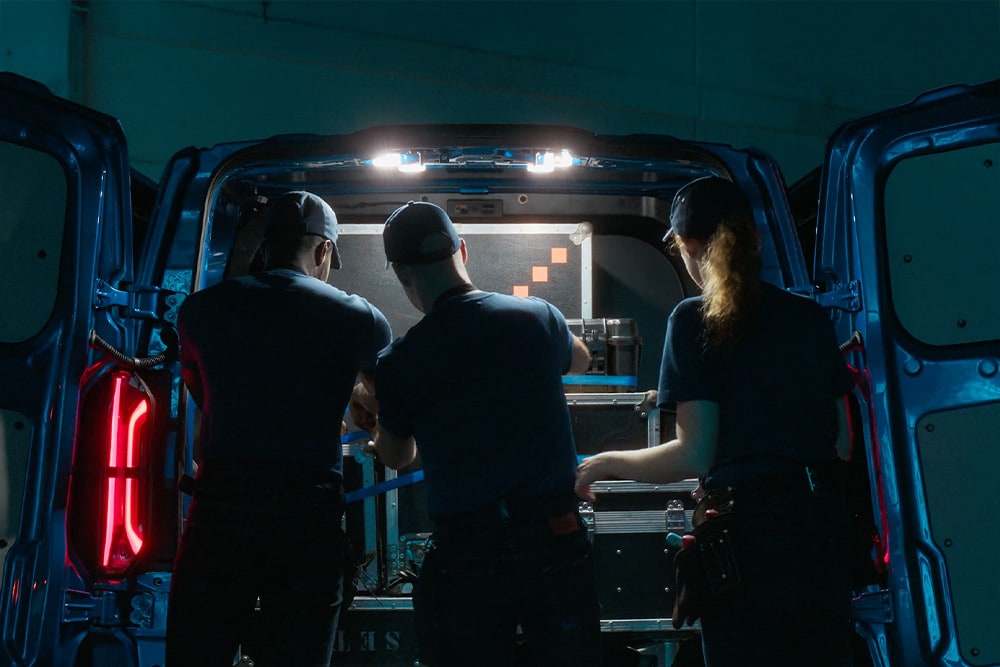 Three people working in the back of a Ford Transit Custom van.