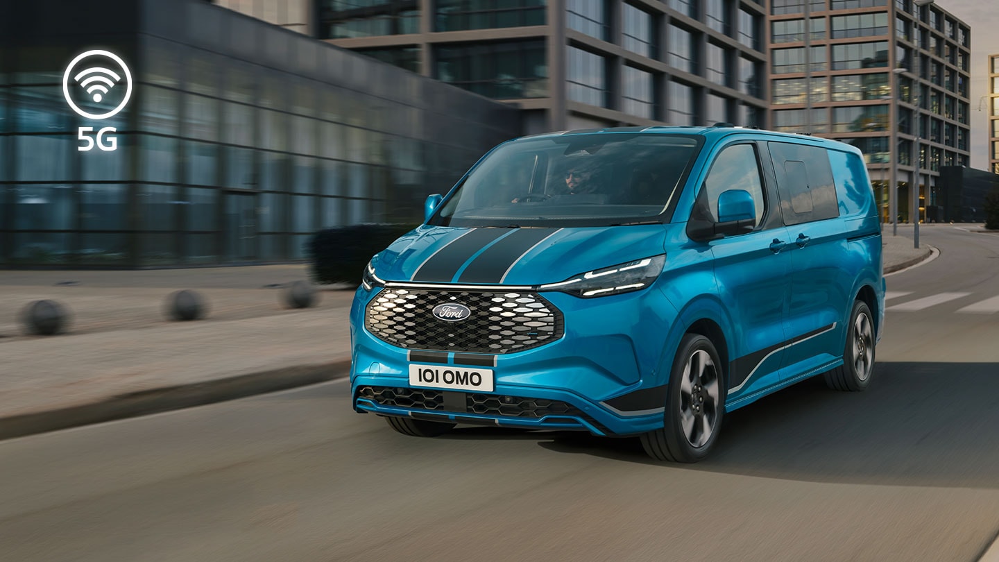 Blue Ford E-Transit Custom electric van driving on a city street.