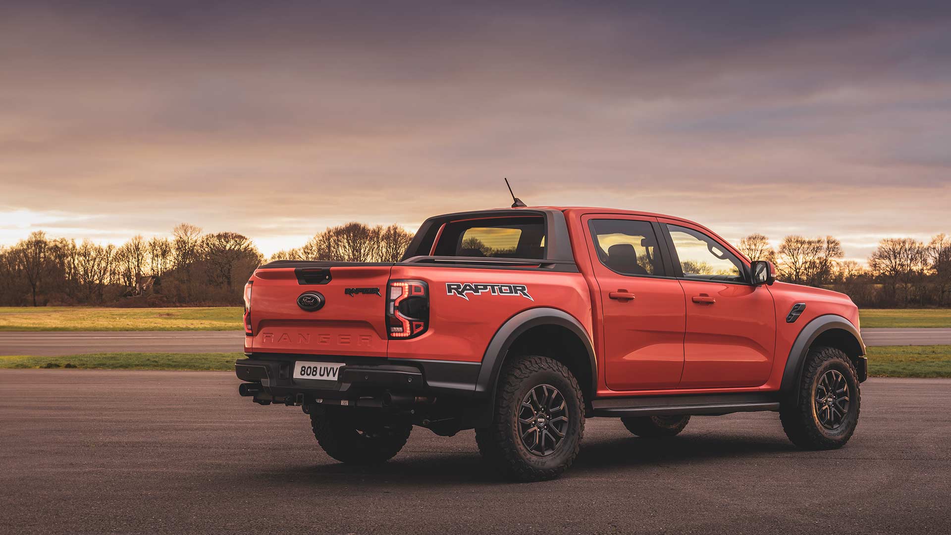 Code Orange Ford Ranger Raptor rear view as it it drives on a track.