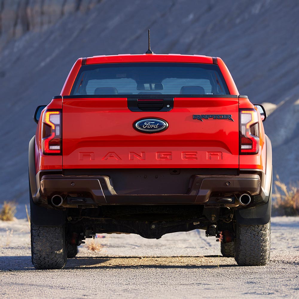 Code Orange Ford Ranger Raptor rear view parked outdoors.