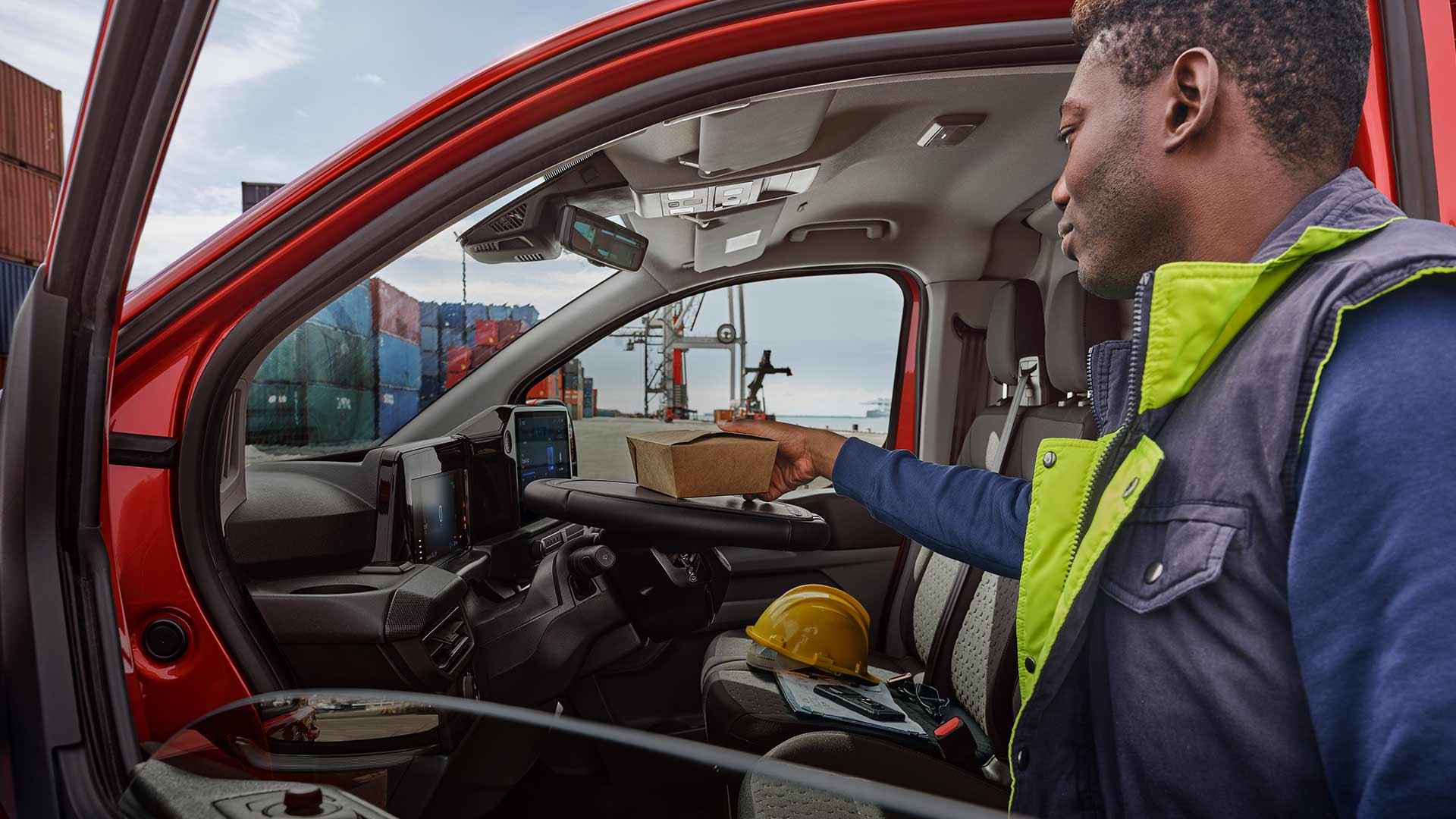 Person placing a package inside a red Ford Transit Custom.