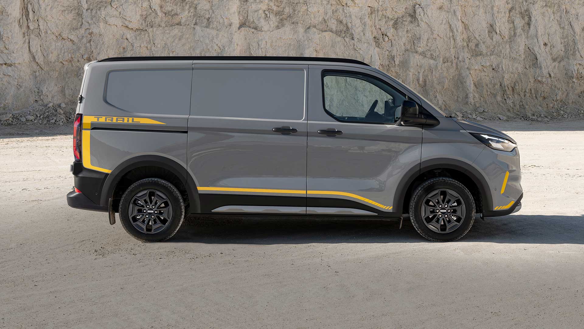 Grey Ford Transit Custom Trail van with yellow accents, side view.