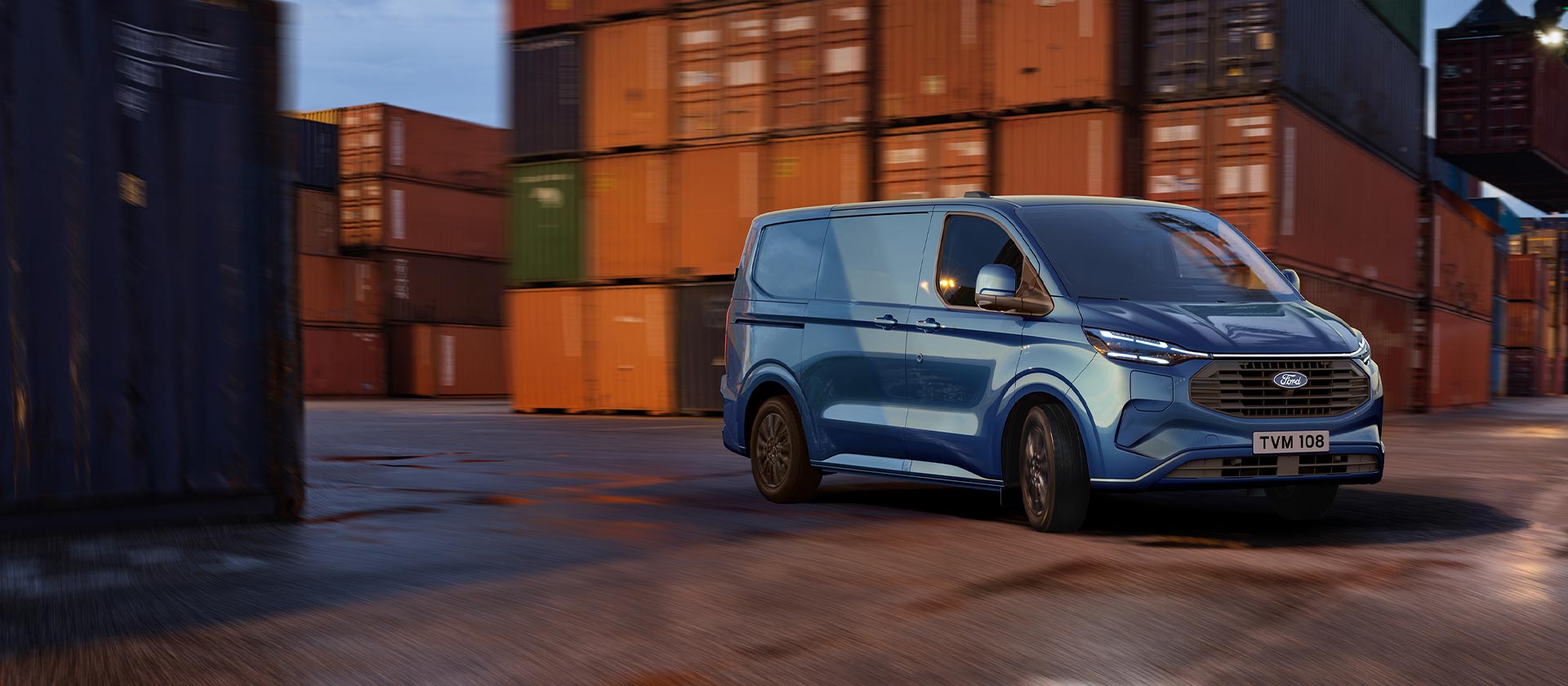 Blue Ford Transit Custom Plug-in Hybrid van drives through a dock yard.