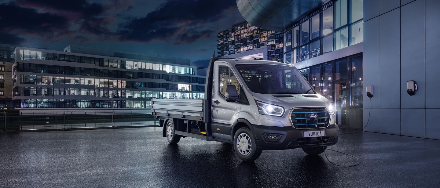 E-Transit side view with the backdrop of city in night with blue electric lights