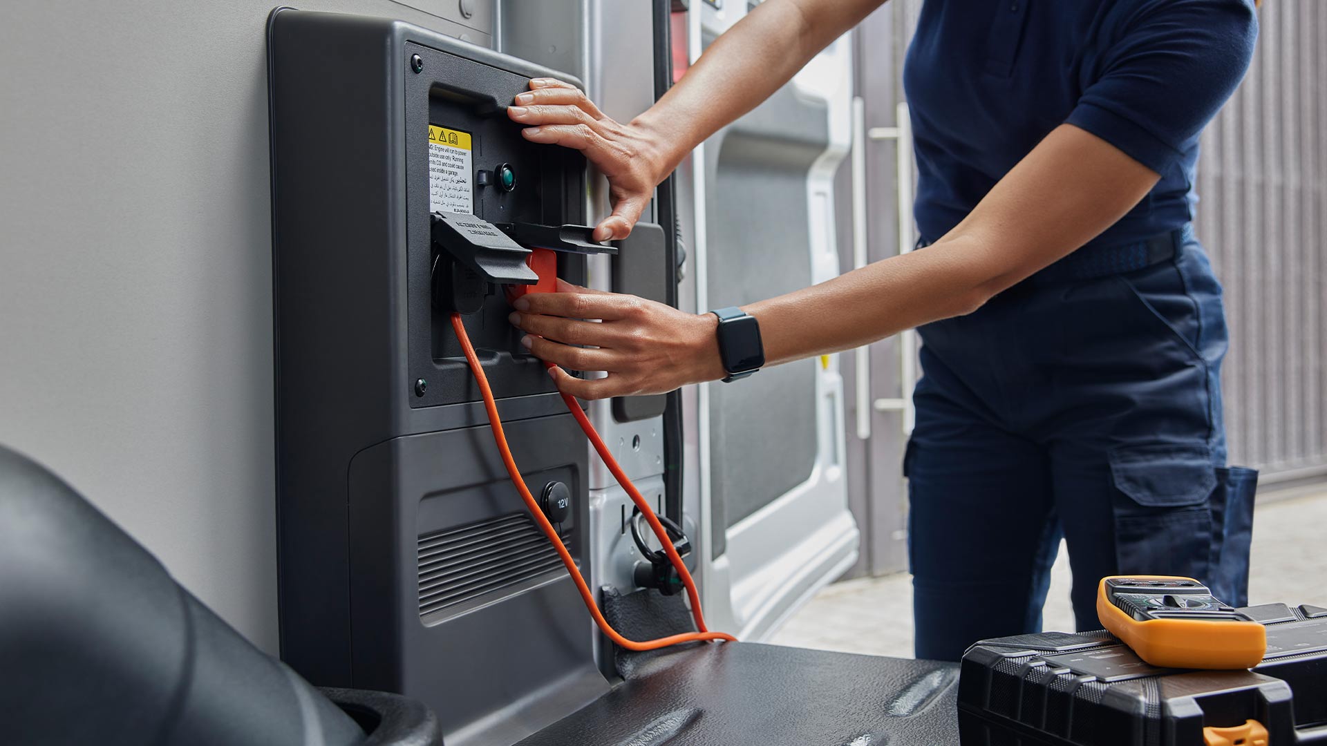 Close-up of a person plugging in a charging cable inside a Ford E-Transit electric van.