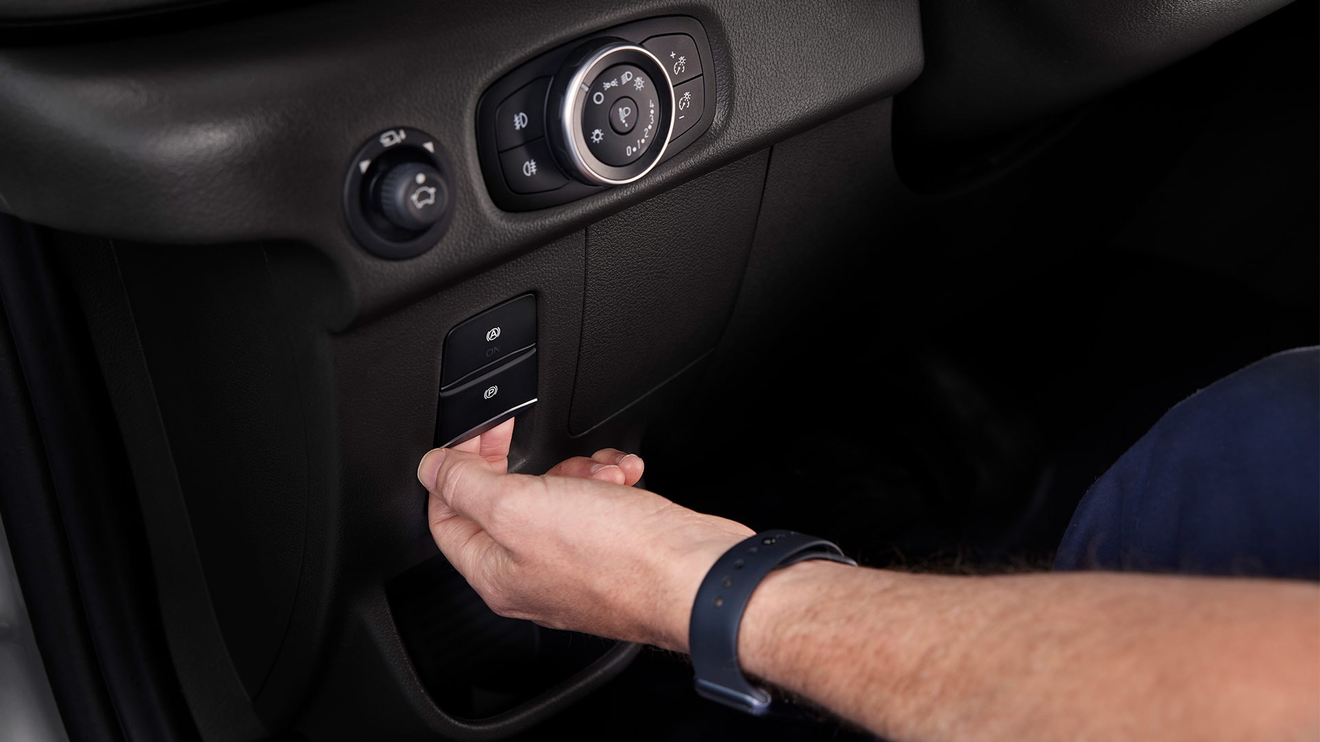 Close-up of a hand pressing a button on the dashboard of a Ford E-Transit electric van.