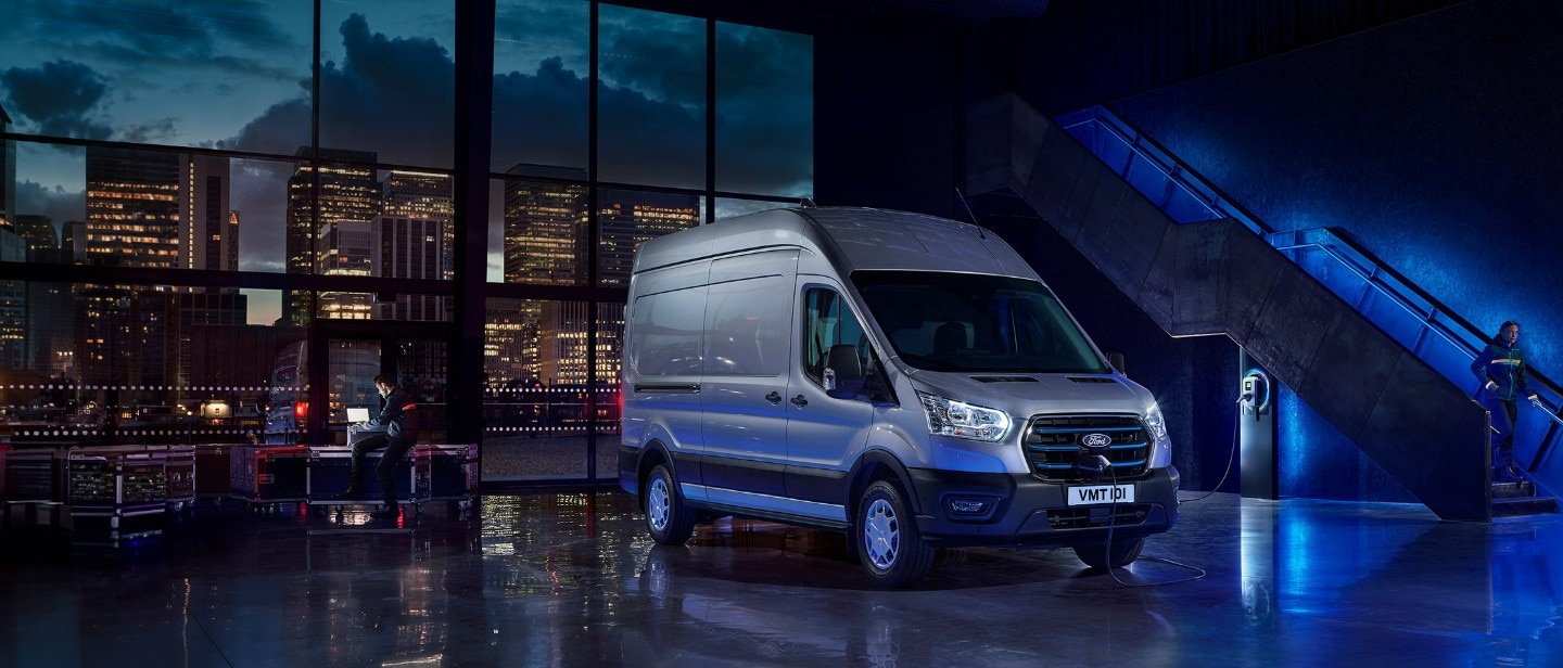 New E-Transit side view with the backdrop of city in night with blue electric lights