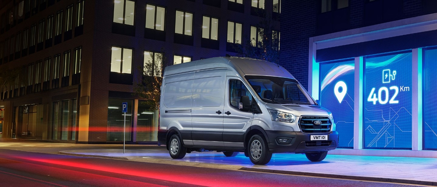 E-Transit side view with the backdrop of city in night with blue electric lights