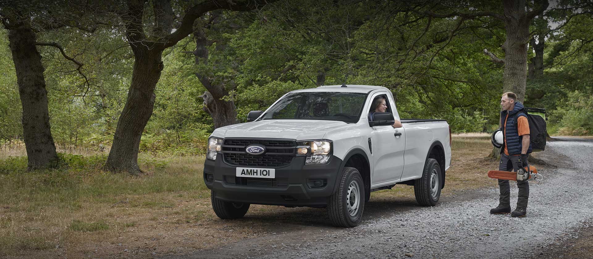 White Ford Ranger Regular Cab parked on the side of a road. A person with equipment stands nearby.