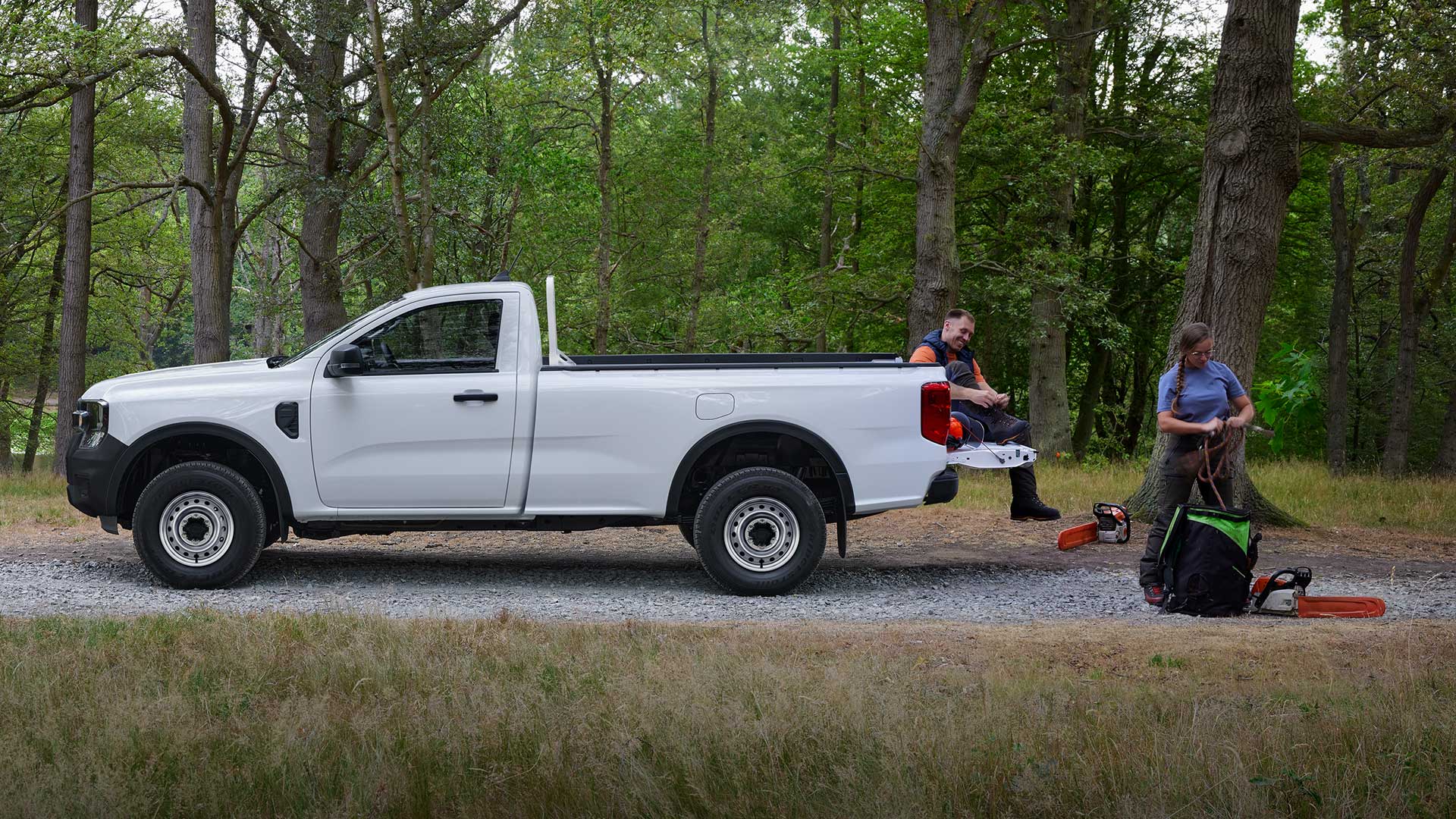 White Ford Ranger Regular Cab, side view, parked in a forest with two people unloading equipment the rear.