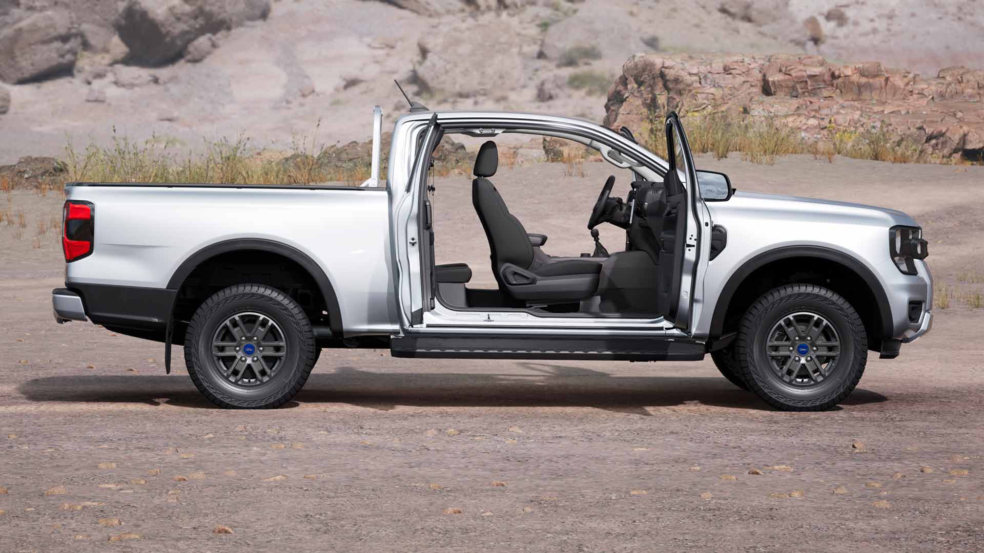 Profile of a silver Ford Ranger XLT Super Cab with open doors, parked in dusty terrain.