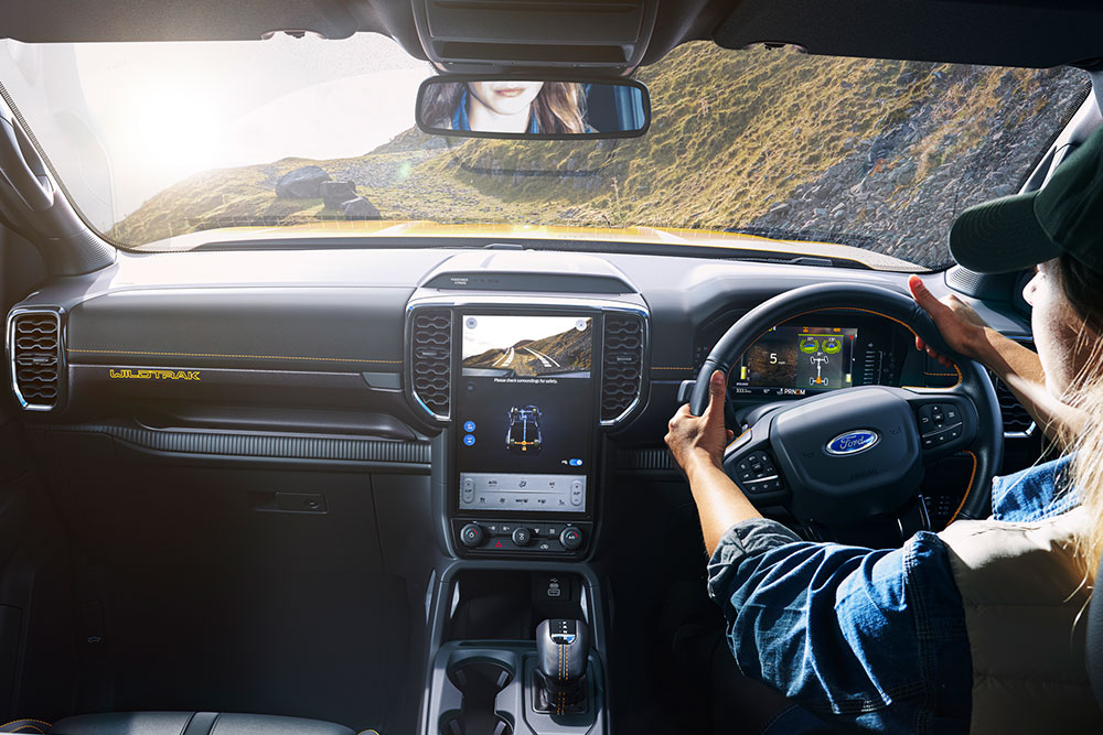 Driver holding the steering wheel of the Ford Ranger while navigating a winding mountain track.