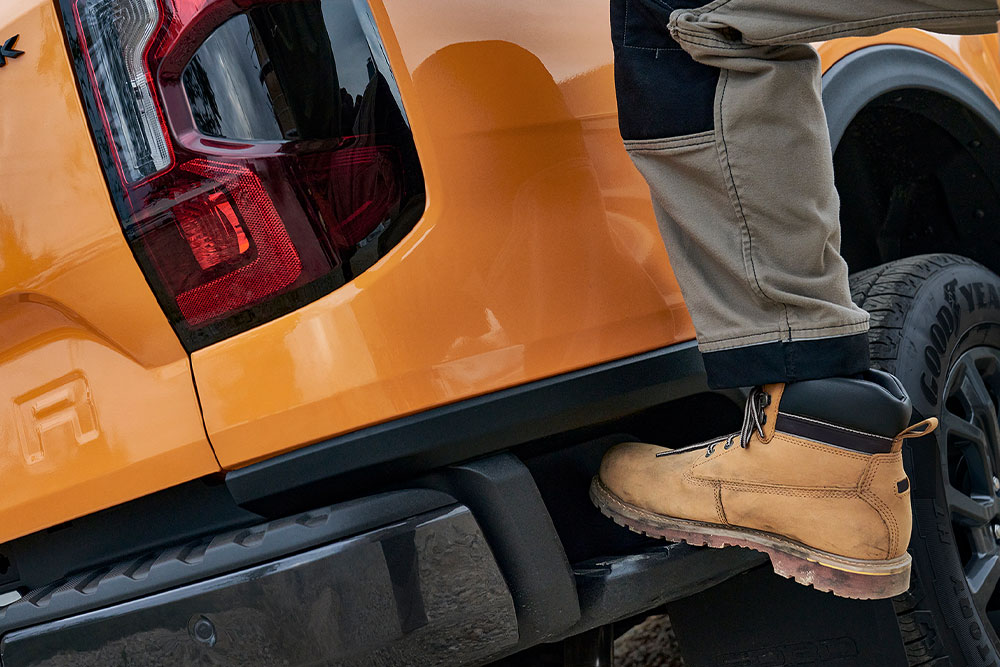 Worker stepping onto the integrated rear step of the Ford Ranger Wildtrak.