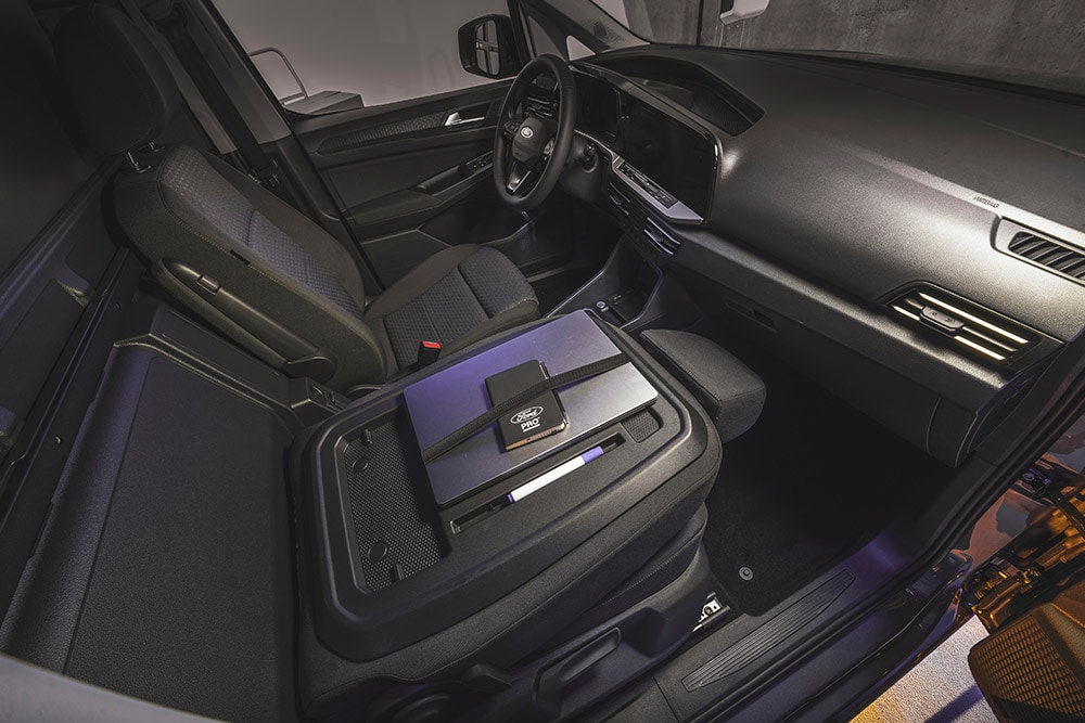 Interior of Ford Transit Connect showing dashboard, seats, a laptop and phone on the centre console.