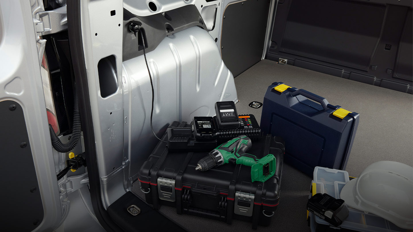 A power drill is plugged into a 12 V socket in the load compartment of a Ford Transit Connect.