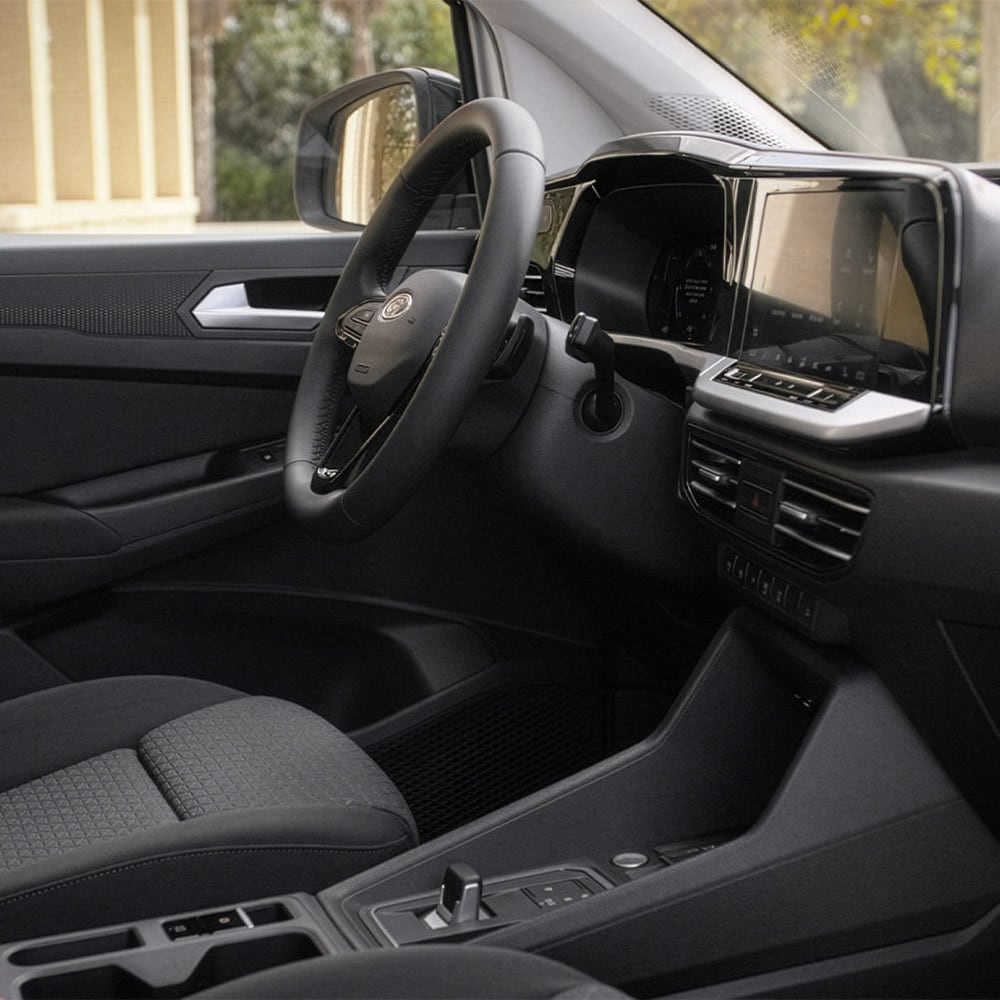 Interior of Ford Transit Connect showing the driver's seat, steering wheel, dashboard and 10-inch touchscreen.