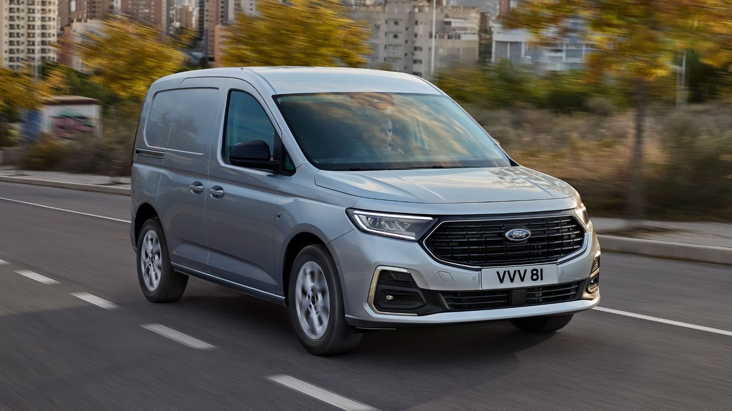 All-New Ford Transit Connect Limited in Stardust Silver driving on a road showing chrome exterior surrounds and automatic headlights. 