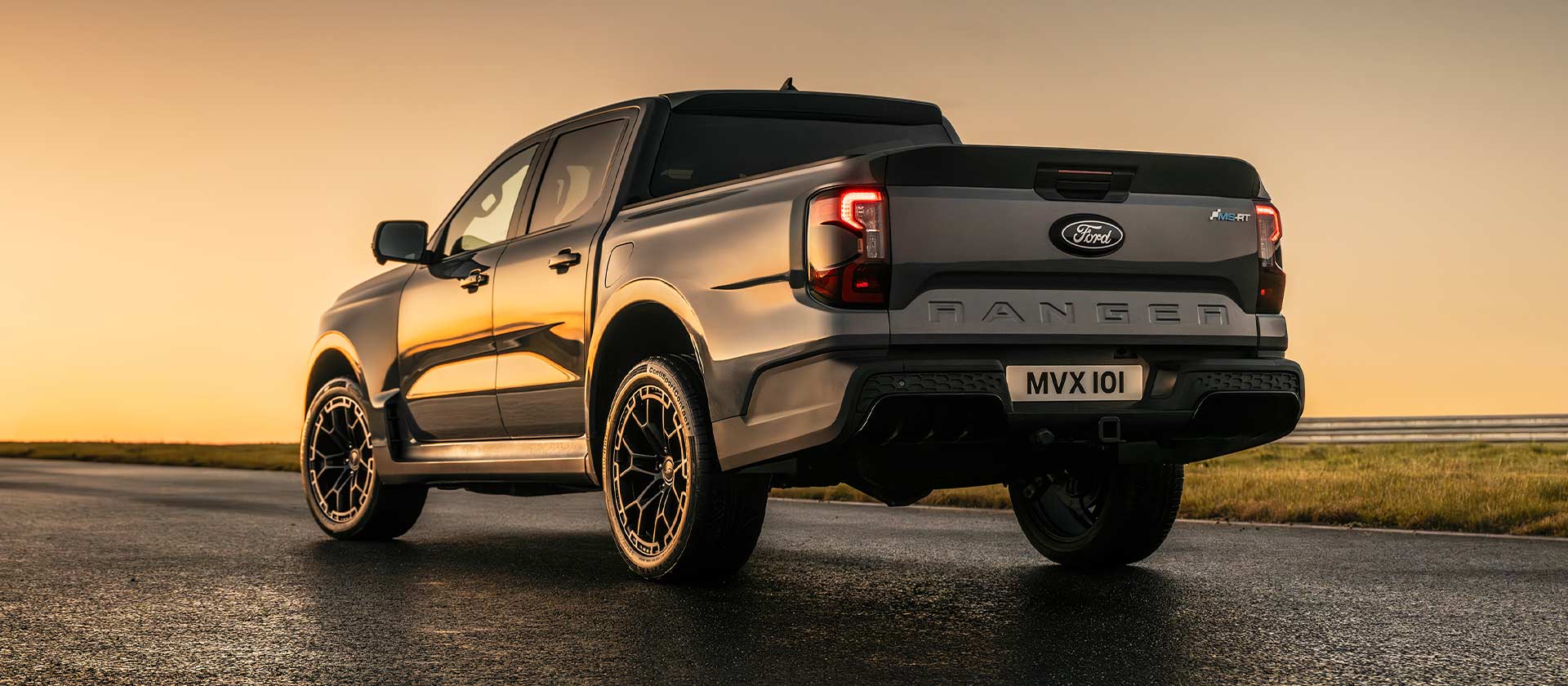 Rear view of a grey Ford Ranger MS-RT with MS-RT badging parked on a track at sunset.