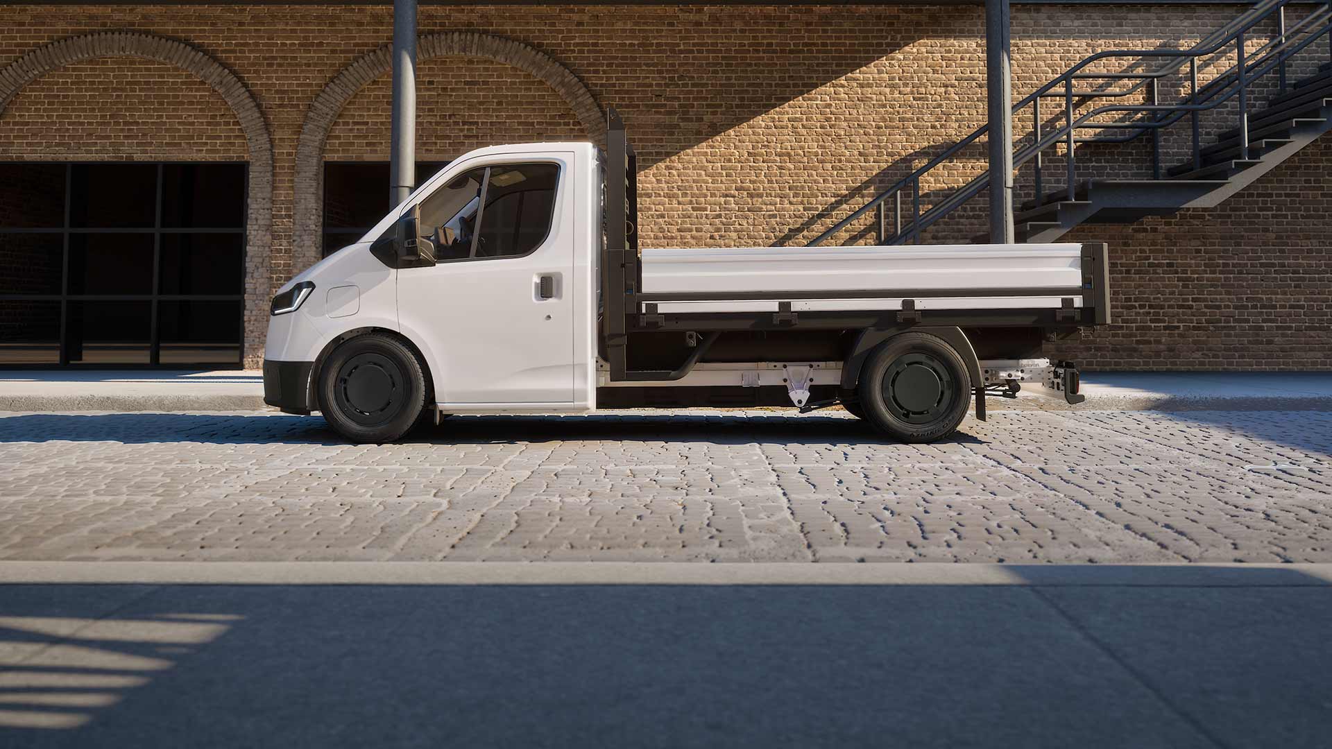 Side view of a white All-New Ford Transit City Chassis Cab van parked in front of a brick building.