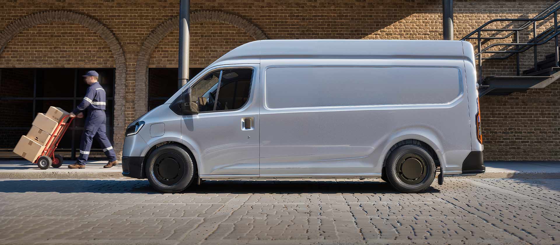 A white Ford Transit City parked next to a brick warehouse. The driver is delivering packages.