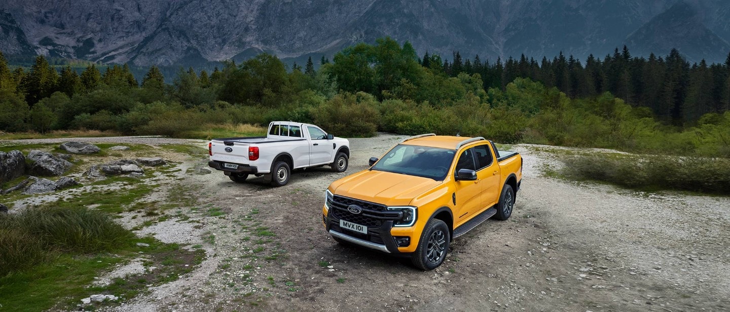 Orange Ford Ranger 3/4 front view on gravel in front of White Ford Ranger 3/4 rear view