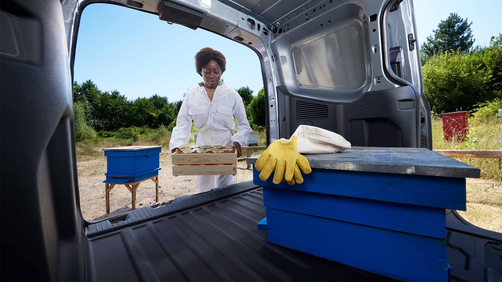 Beekeeper loading honey into a Ford Transit Courier