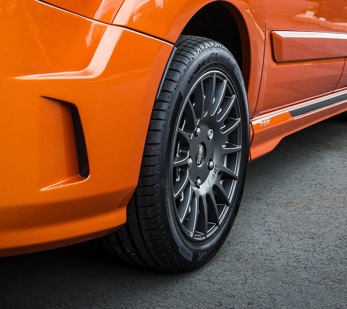 Closeup of a rear wheel on an orange Ford Transit Custom MS-RT