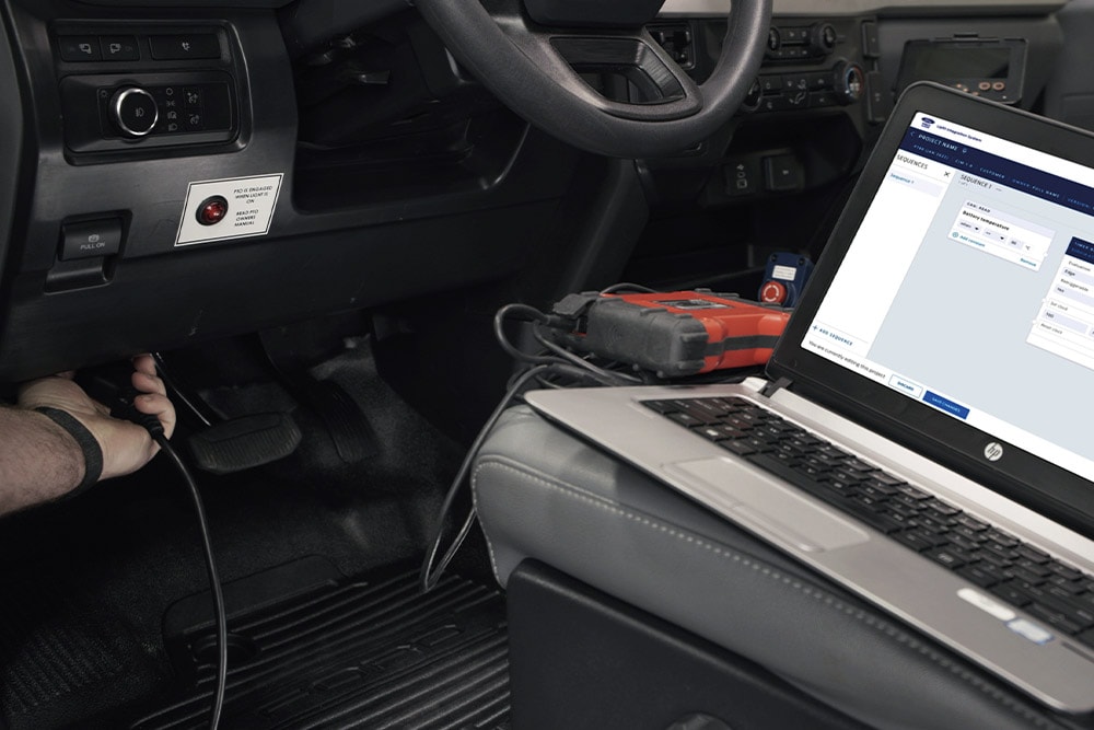 Close up view of laptop connected to a Ford vehicle dashboard.