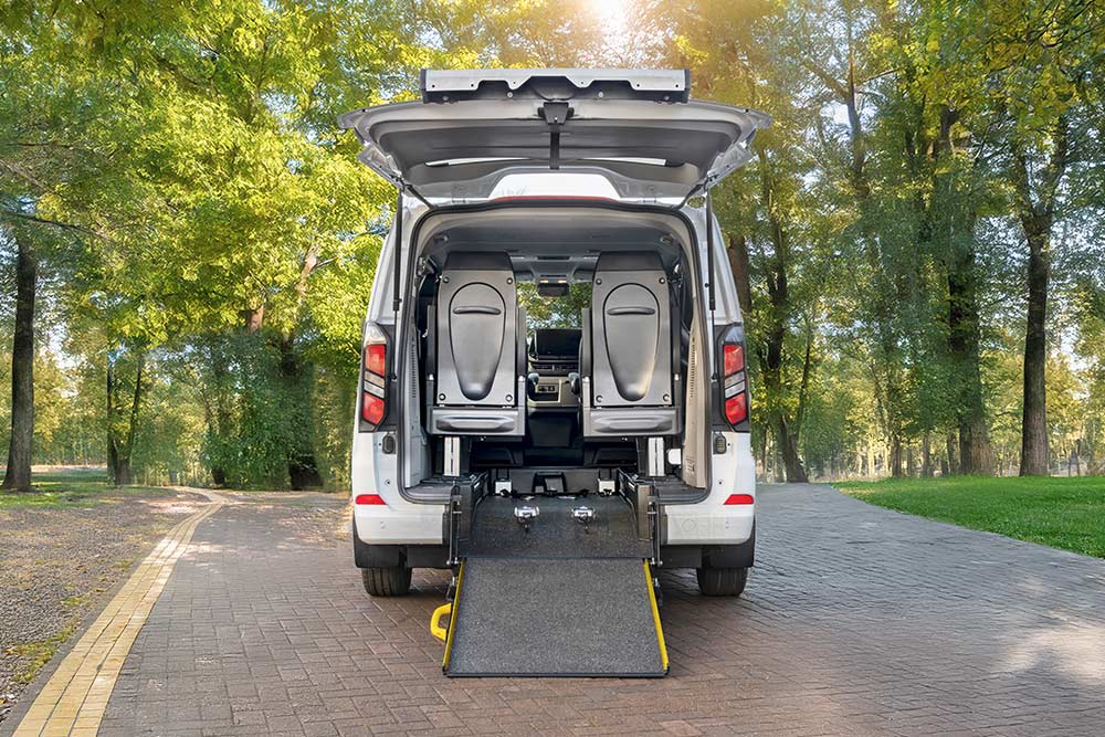 Rear view of a white Ford Transit Custom with an open tailgate and deployed wheelchair ramp.