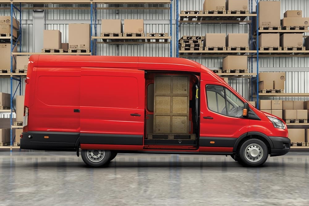 A red Ford van parked inside a warehouse with shelves of goods, symbolizing "Goods in Transit" coverage.