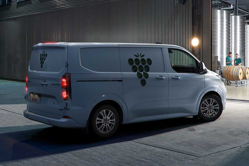 A white Ford van parked outside a warehouse door at night.