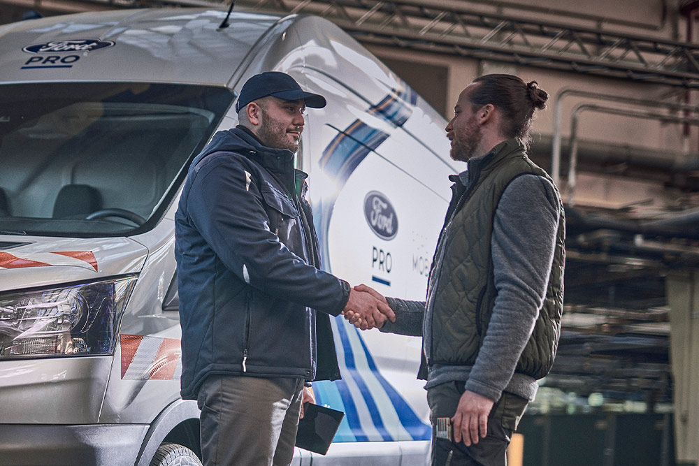 Ford Pro technician talks with customer, a Ford Pro Mobile Service van visible in background.