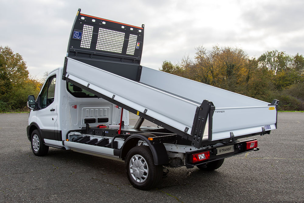 White Ford Pro Chassis Cab with a raised flatbed parked in a paved lot.