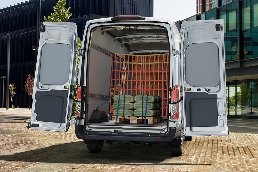 A rear view of the inside of a white Ford van parked near office buildings.