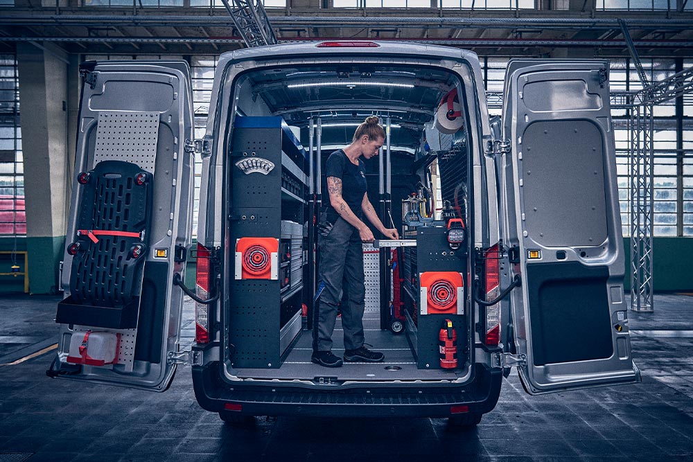 Technician inside the back of a Ford van, checking data on his laptop.