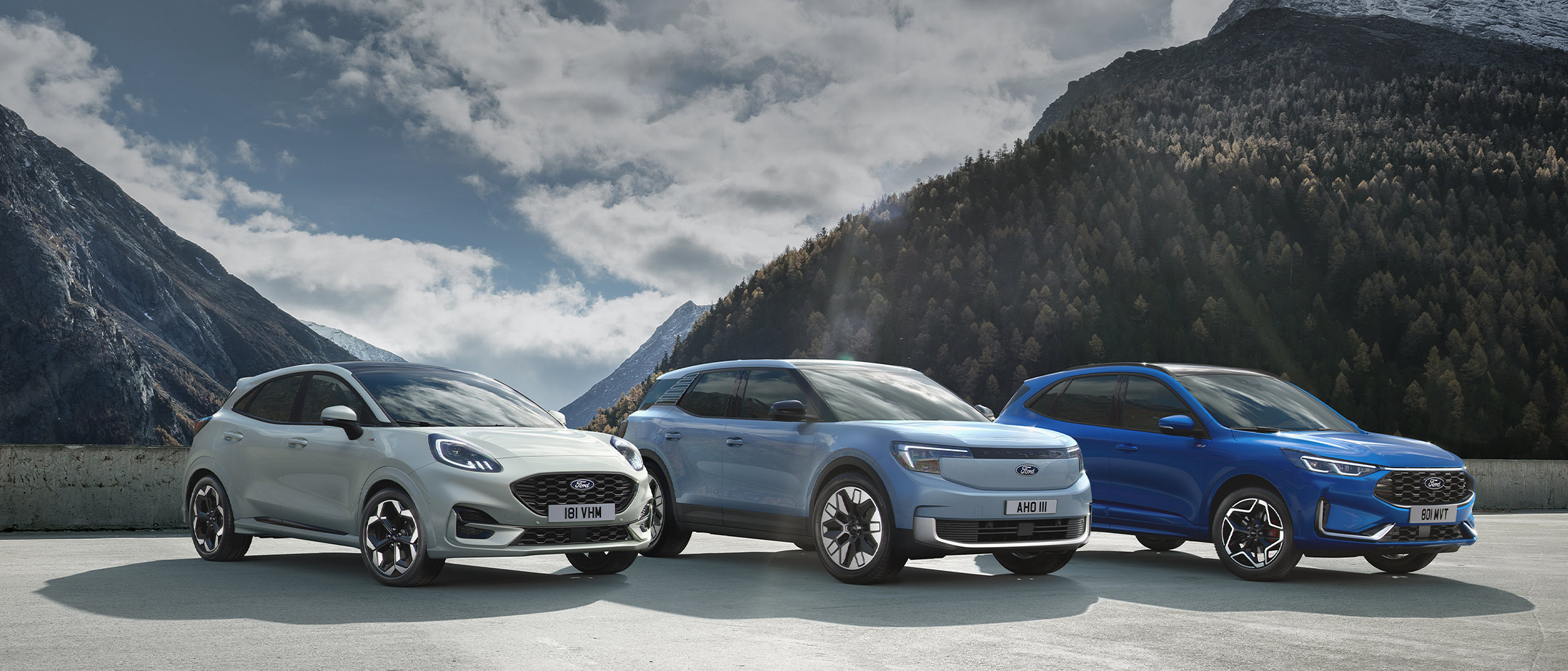 A Ford Puma, Explorer, Kuga, and Mustang Mach-E parked against a snowy mountain backdrop.