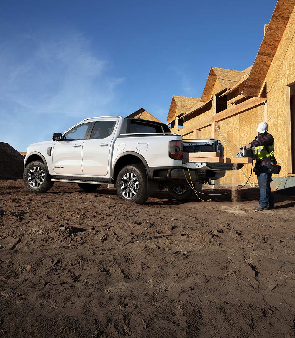 White Ford truck parked at construction site, buildings under construction in the background.