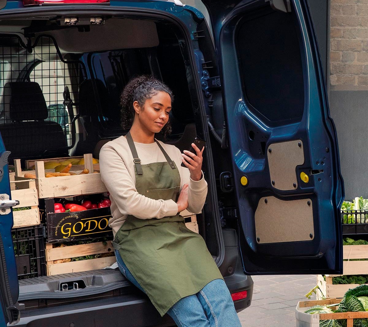 Woman with phone leaning on to Ford Transit Courier