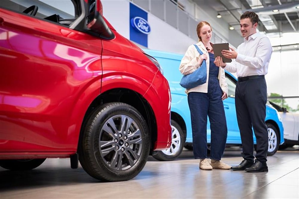 A woman talking to a dealer in front of a car