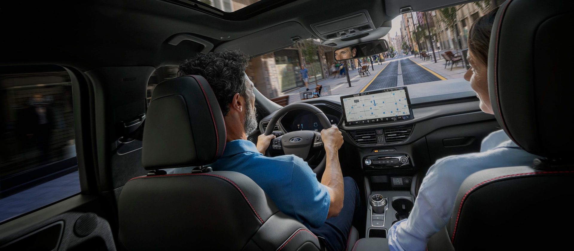 Passengers in a Ford vehicle with the SYNC digital screen displayed to help navigate a city route.