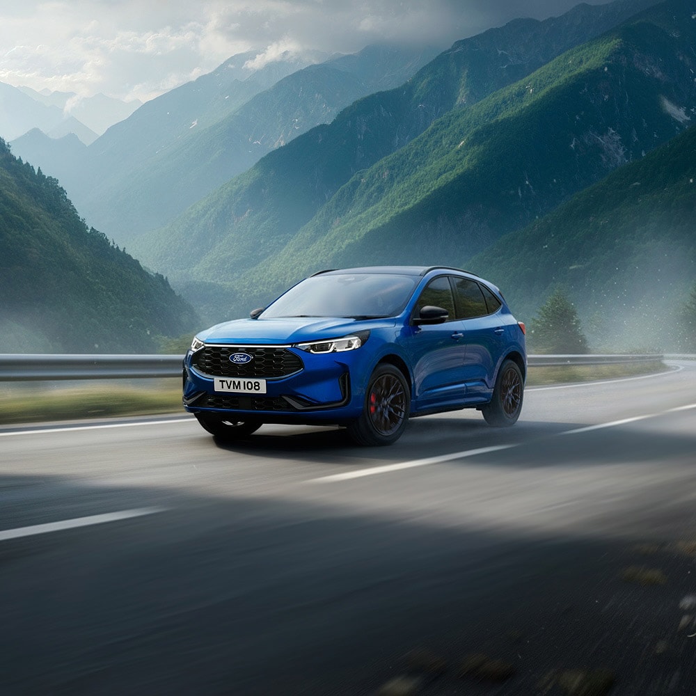 Blue Ford Kuga: Front 3/4 view of a blue Ford Kuga driving on a winding mountain road.