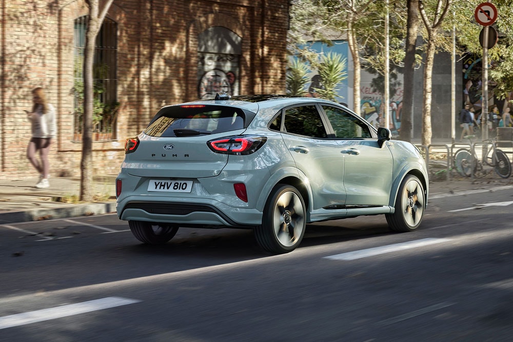 A light grey Ford Puma driving on a city street, seen from the rear three-quarter angle.
