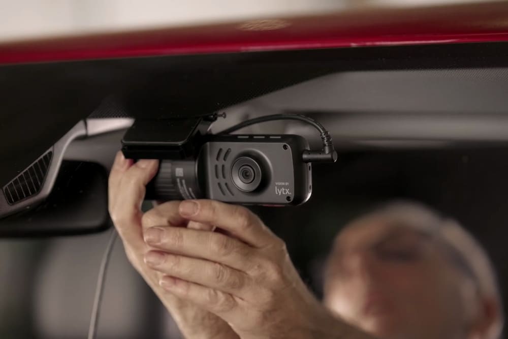 Dashcam unit mounted on the windscreen of a Ford Transit Custom, with a person observing.