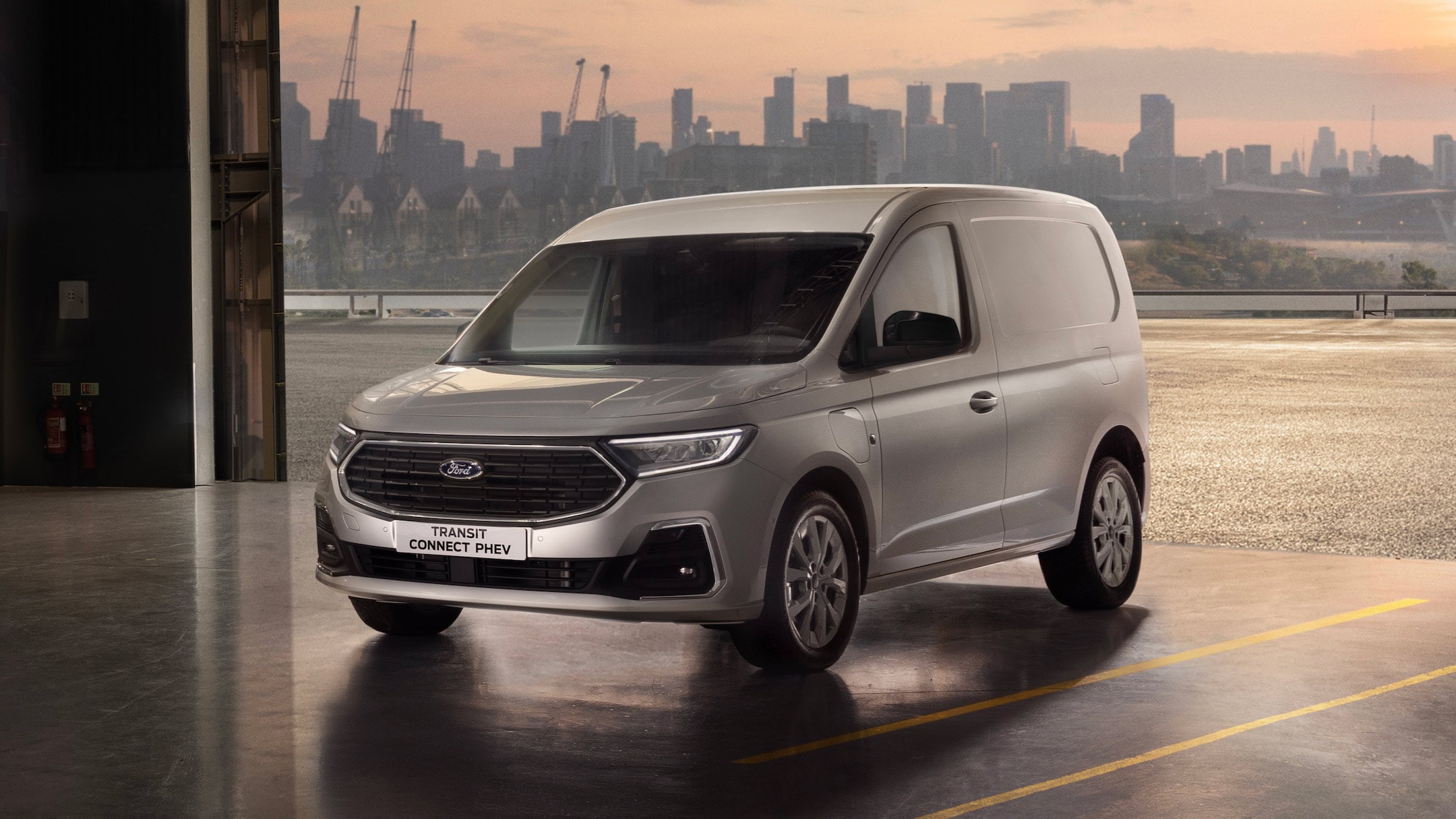 Silver Ford Transit Connect PHEV van with a city skyline in the background.
