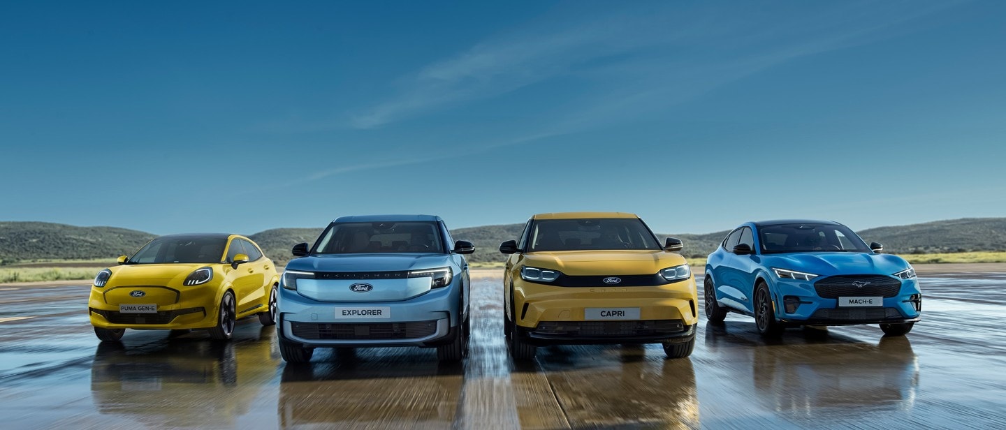 Four Ford EVs: Yellow Puma Gen-E, blue Explorer, yellow Capri, and blue Mustang Mach-E, lined up on a wet surface.
