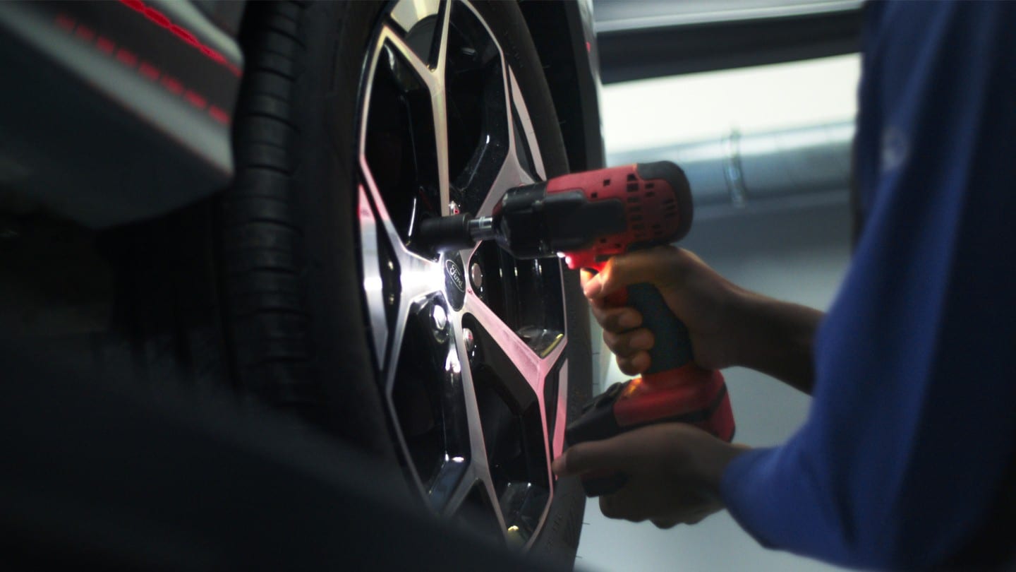A Ford technician uses a power tool to change a tyre in a Ford service centre. A Ford technician uses a power tool to change a tyre in a Ford service centre.