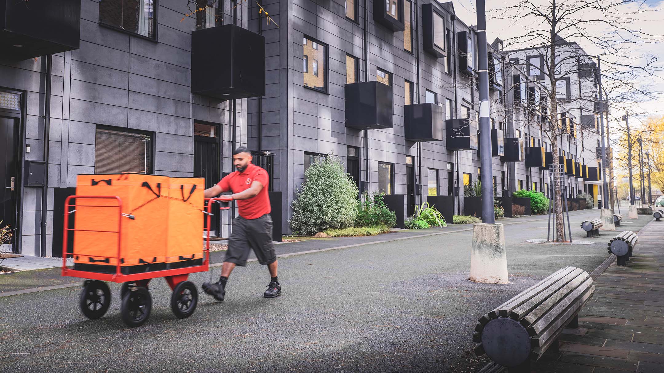 Man pushing a trolley with a package through a residential area