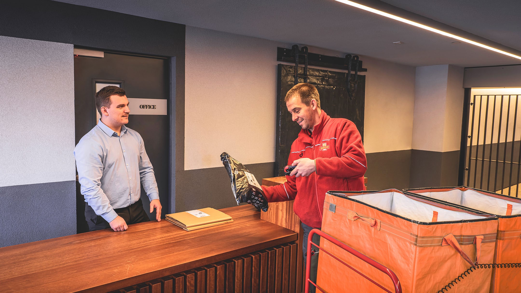 Delivery man handing over a package to a man standing behind a reception desk