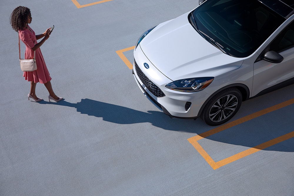 Woman checking phone stood next to parked car