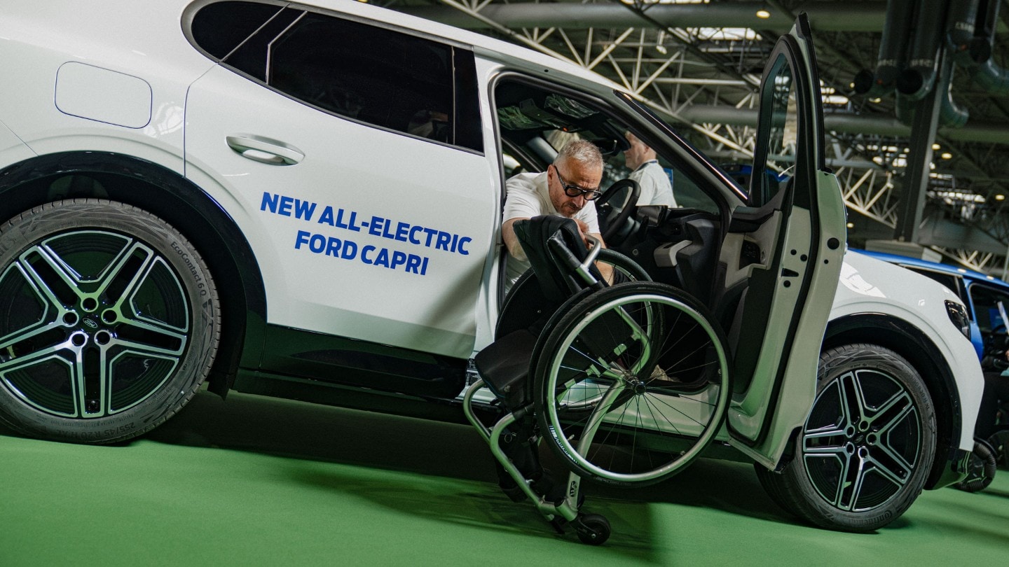 Jason Richards in a wheelchair next to a white Ford Capri with "NEW ALL-ELECTRIC FORD CAPRI" on the side.